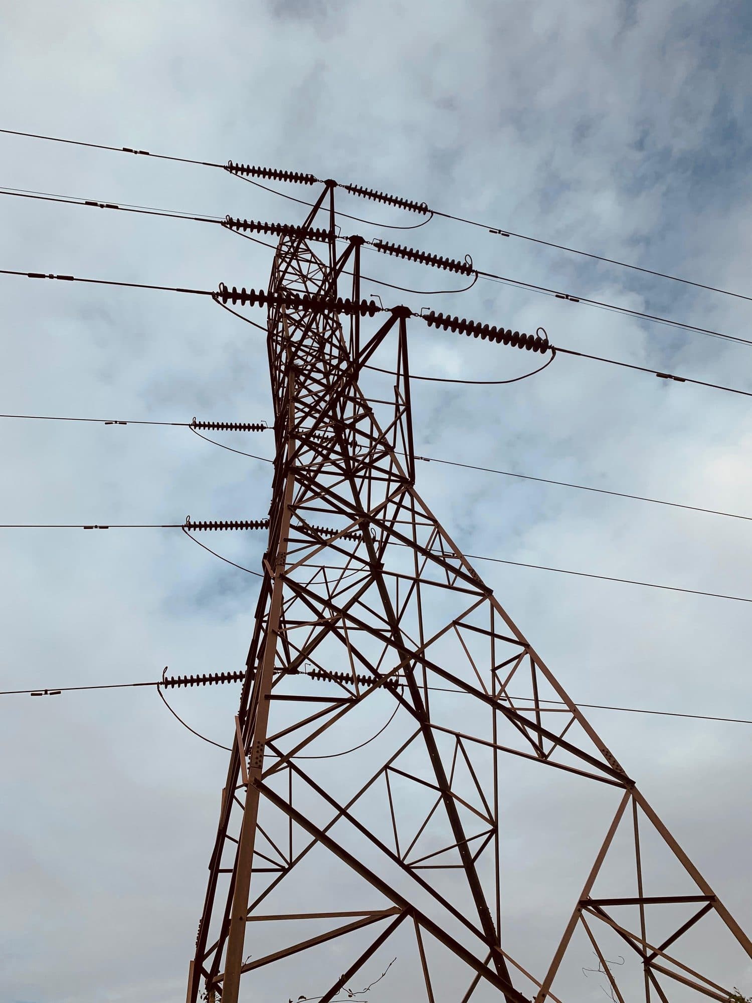Looking up a lattice tower to its cross-arms and insulators
