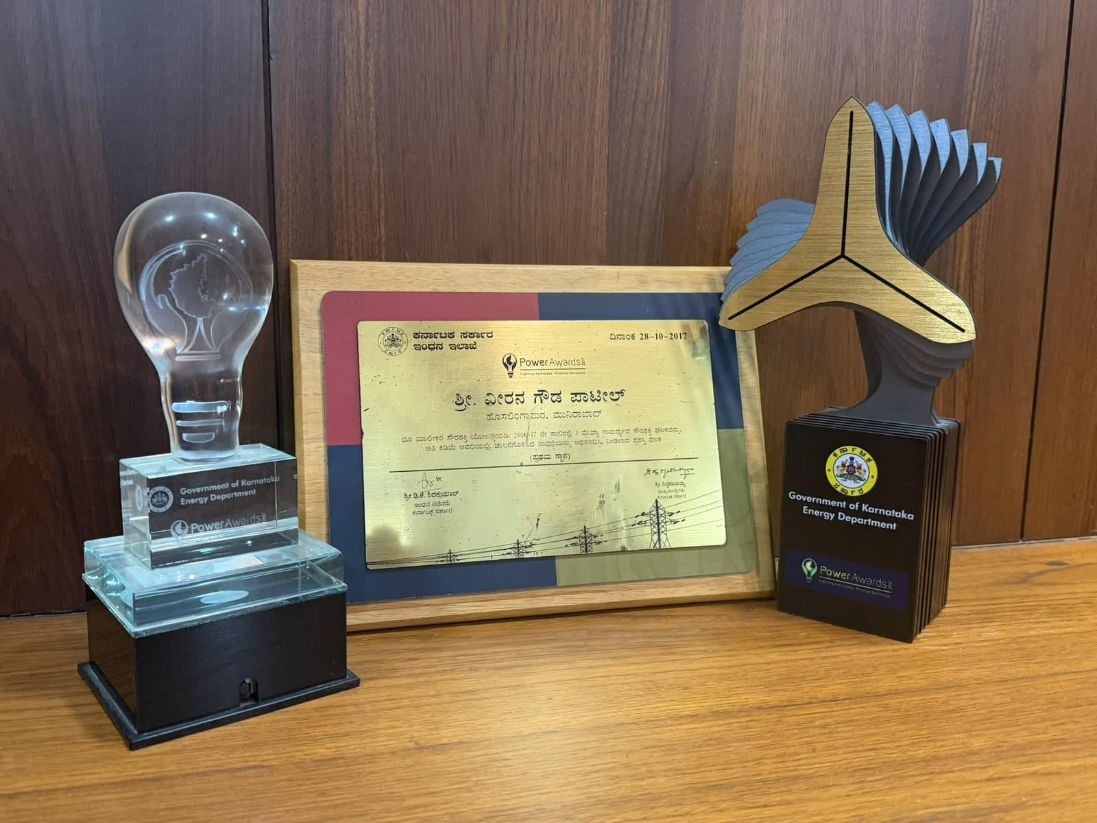 The Power Awards 2017 plaque of the Government of Karnataka's Energy Department, between its crystal and winged trophies