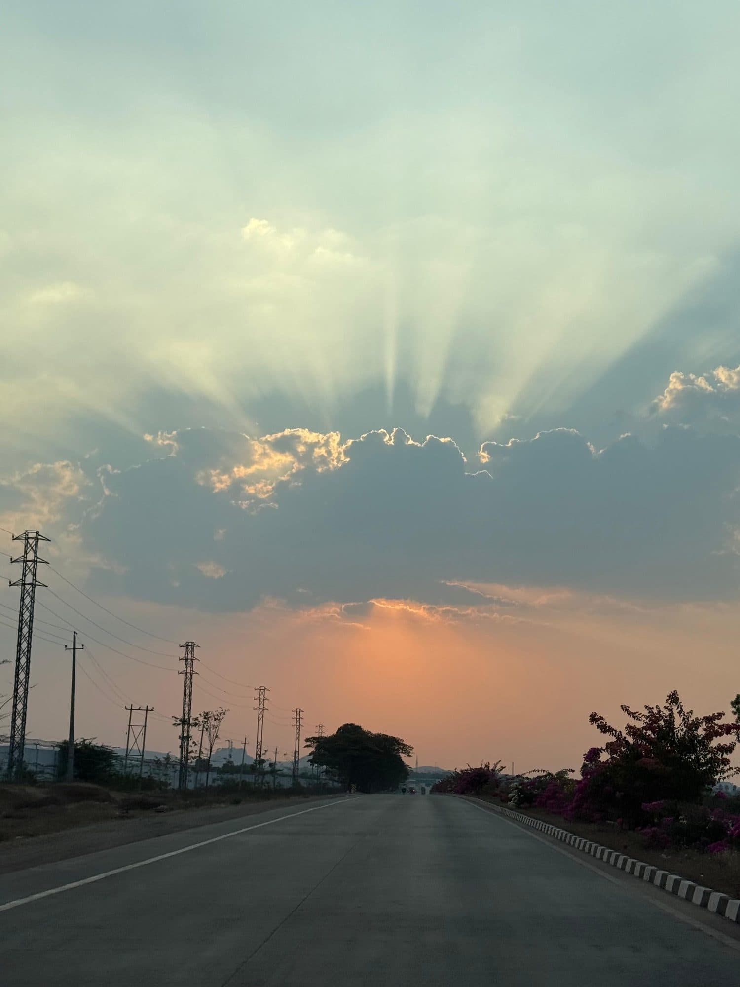 Sun rays over a highway, towers along the road