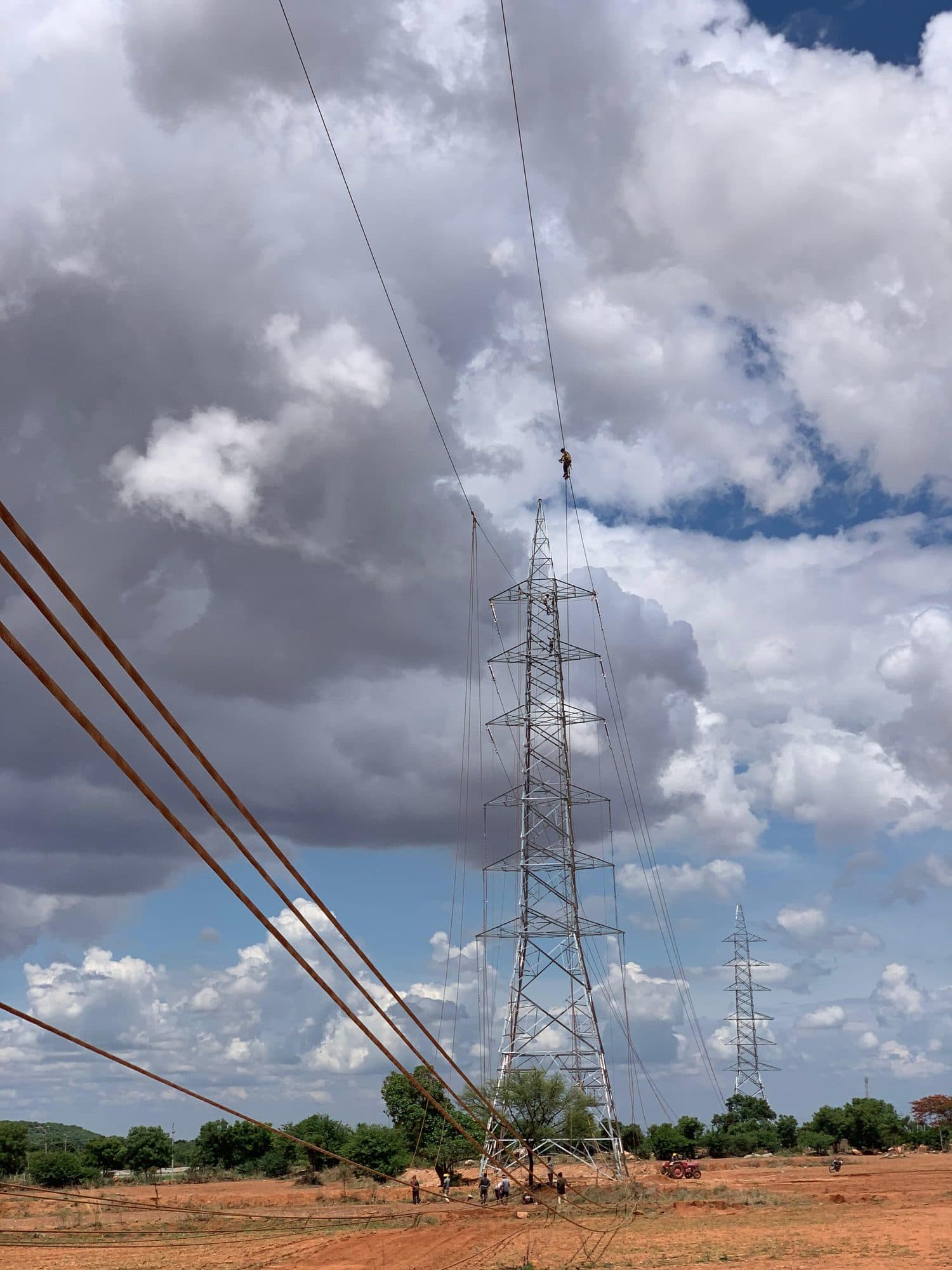 A transmission tower under towering white clouds