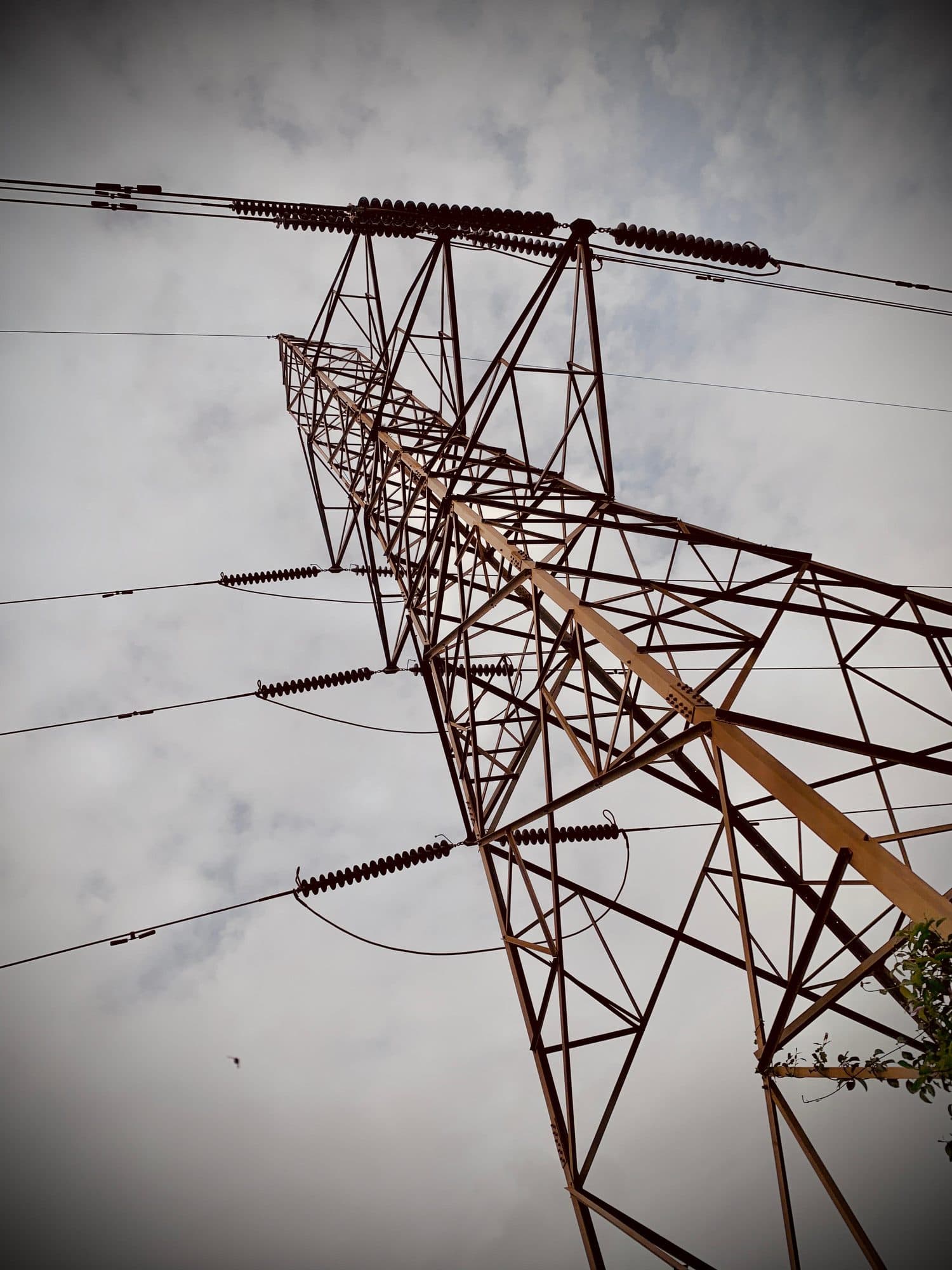 A tower's cross-arm and conductors against grey cloud