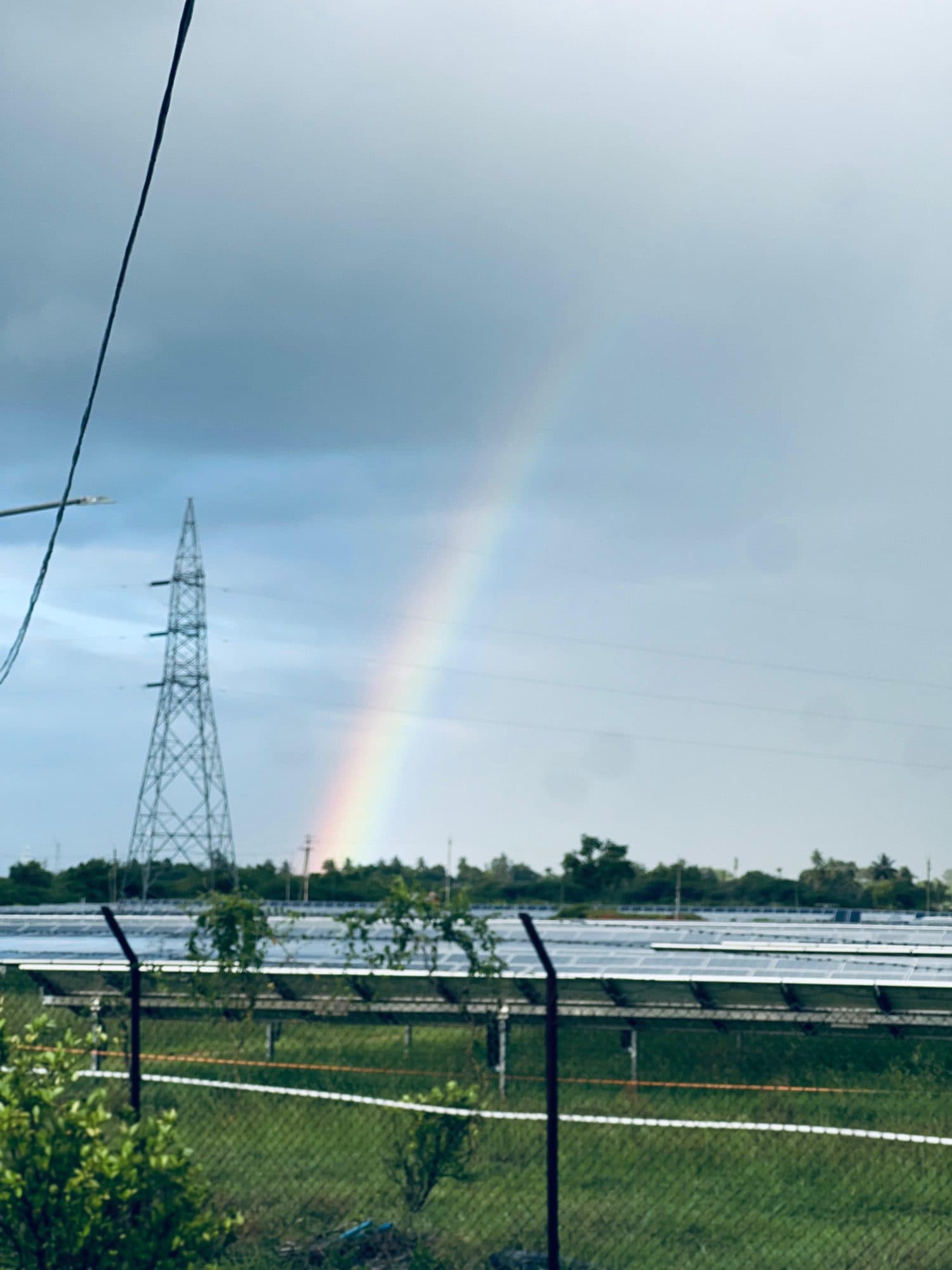 A rainbow beside a transmission tower