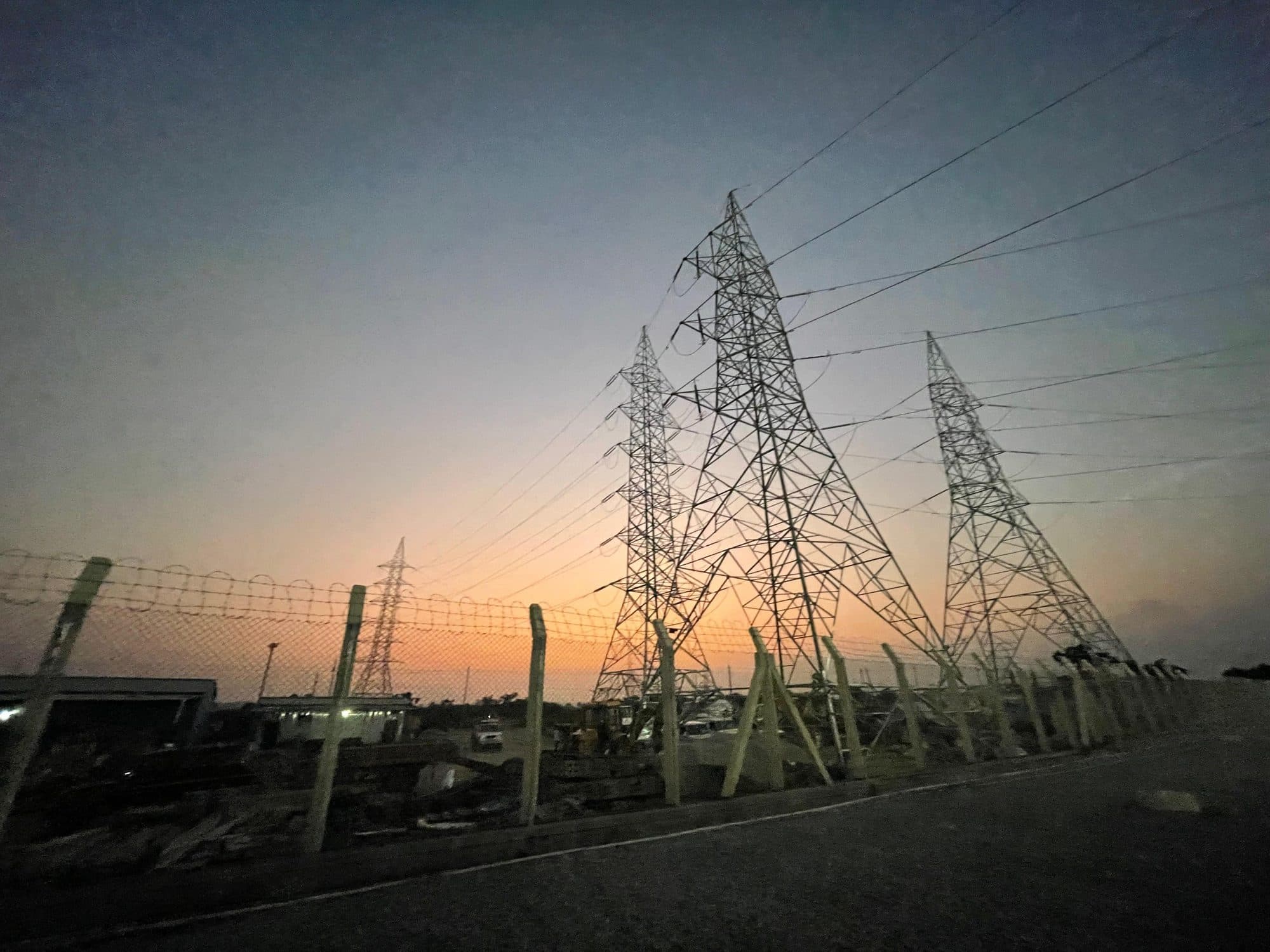 Transmission towers at dusk beyond the station fence