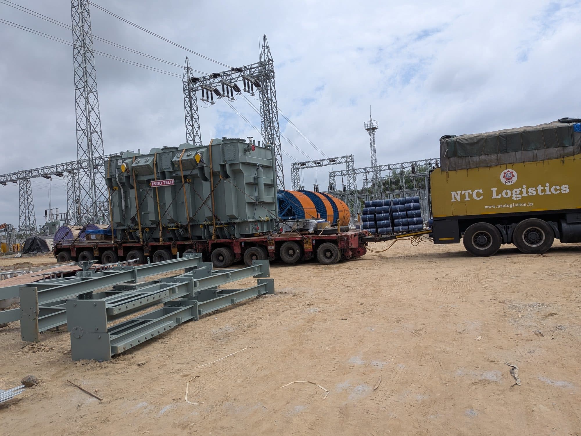 The transformer on its trailer beside the switchyard, steel structures stacked in front